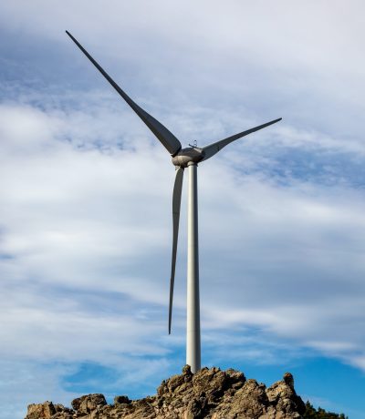 Wind turbine, renewable energy on a rocky hill.